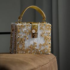 Discover the modern elegance of the Acrylic Box Handbag. This handbag redefines luxury with its box-shaped silhouette and gold-plated floral embellishments. Its sleek design and secure turn-up lock add a touch of sophistication. Perfect for a contemporary outfit, this vegan & cruelty-free handbag is a structural marvel that effortlessly blends style and function. Glitter Clutch Bag, Lug Bags, Party Purse, Retro Mode, Vintage Purses, Crossbody Wallet, Branded Handbags, Small Shoulder Bag, Square Bag