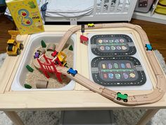 a toy train set sitting on top of a wooden table next to a play mat