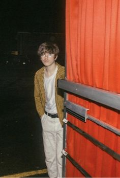 a young man standing in front of a red door