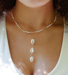 Release your inner beach beauty with our Triple Cowrie Shell Necklace! Handmade with three authentic cream-colored cowrie shells set onto a sterling silver or 14k gold filled chain, this pendant is sure to bring summer vibes to every season! Since each shell is natural, there will be slight variations from one piece to the next. Some shells are longer/wider, while others are more narrow or short. If you have a preference, let us know. Cowrie Shell Meaning: Once used as currency in many cultures Beach Season Shell Strand Jewelry, Gold Coastal Shell Jewelry, Gold Coastal Jewelry For Vacation, Coastal Style Gold Strand Jewelry, Coastal Gold Jewelry For Vacation, Cowrie Shell Strand Jewelry For Beach Season, Shell Strand Jewelry For Vacation, Beachy Gold Beaded Jewelry, Elegant Shell Jewelry For Beach Season