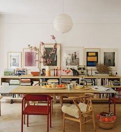 a dining room table surrounded by bookshelves and pictures