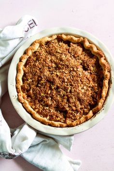 a pie sitting on top of a white plate next to a napkin and spoons