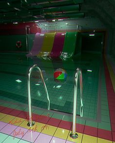 an empty swimming pool with colorful tiles and railings on the floor, in front of a green tiled wall