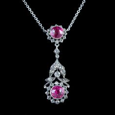 A glamorous antique Edwardian lavaliere necklace from the early 20th Century featuring a beautiful, floral dropper decorated with glistening white pastes and two larger pink pastes that together simulate the beauty of diamonds and pink sapphires.   The silver dropper is suspended from a silver cable chain and held by a ring clasp.  It's in excellent condition and would be perfect for a wedding or special occasion.  WEIGHT: 9 grams MEASURES: Dropper Width 15mm x Height 50mm x Depth 7mm - Chain me Vintage Pendant Necklace With Diamond Accents, Pink Pendant Necklace With Jewels, Vintage Diamond Gemstone Necklace, Antique Hallmarked Pink Jewelry, Antique Pink Hallmarked Jewelry, Pink Antique Hallmarked Jewelry, Vintage Diamond Necklace With Gemstones, Pink Oval Victorian Jewelry, Vintage Pink Gemstone Jewelry