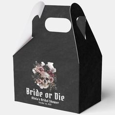 a black paper bag with white flowers on the front and side, featuring an image of a skull