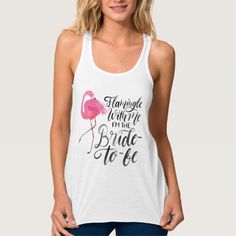 a woman wearing a white tank top with a pink flamingo on the front and black lettering