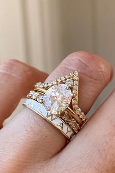 a woman's hand wearing a gold ring with a heart shaped diamond on it