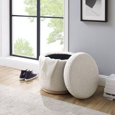 a pair of shoes is sitting on the floor next to a white ottoman and window