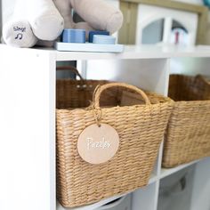 two wicker baskets with personalized tags on them are sitting on a shelf in a children's playroom