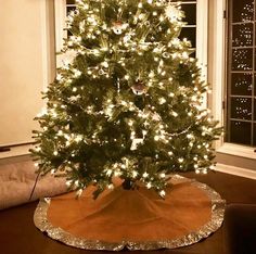 a lit christmas tree in a living room next to a window with lights on it