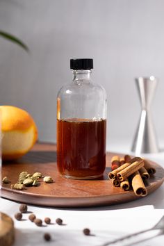 a glass bottle filled with liquid sitting on top of a wooden tray next to cinnamons