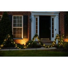 christmas lights decorate the front of a brick house with white trimmings and wreaths