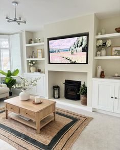 a flat screen tv mounted on the wall above a fireplace in a living room with white furniture