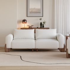 a white couch sitting on top of a wooden floor next to a table and lamp