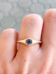 a woman's hand with a gold ring and blue sapphire stone on the middle finger