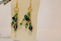 These pierced earrings have three hanging and swinging dangles.  Each has green pearls in shades of green and a green crystal. Green Dangle Chandelier Earrings, May Birthstone Crystal Dangle Earrings For Party, Handmade Green Earrings For Party, Green Chandelier Earrings For Party, Handmade Green Chandelier Earrings For Party, Green Dangling Bead Chandelier Earrings, Green Dangle Earrings For Pierced Ears, Green Dangle Jewelry For Party, Green Dangle Party Jewelry