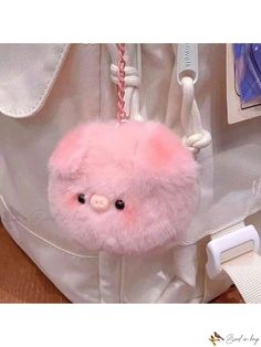 a pink teddy bear hanging from the side of a bag