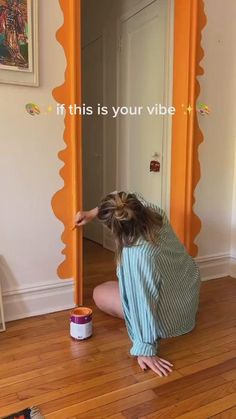 a woman kneeling down on the floor in front of a mirror with an orange frame