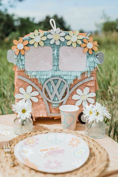 a table topped with plates and vases next to a small wooden house shaped like a camper