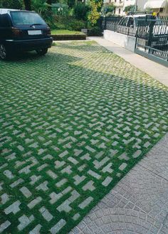 a black car parked on the side of a road next to a green grass covered parking lot