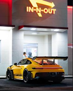 a yellow sports car is parked in front of a fast food restaurant that has an in - n - out sign above it