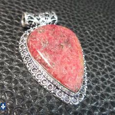 a red heart shaped stone sitting on top of a black table next to a silver chain