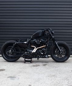 a black motorcycle is parked in front of a garage door and it's frame still attached to the bike