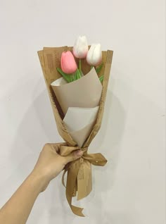 someone is holding a bouquet of tulips wrapped in brown paper