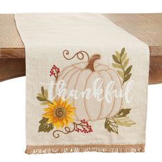 a white towel with a sunflower and the word thank on it hanging from a wooden rail