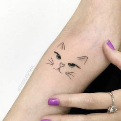 a woman's hand with a cat tattoo on her left wrist and the other arm