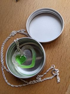 an open tin can sitting on top of a wooden table next to a green heart