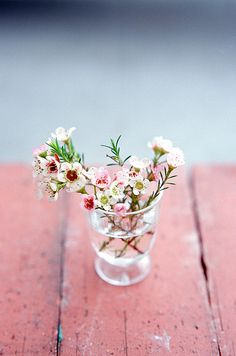 a small glass vase filled with flowers on top of a wooden table