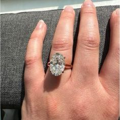 a woman's hand with a diamond ring on top of her finger and the other hand holding an engagement ring