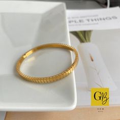 Introducing our elegant gold-plated stainless steel open hinged bangle, a perfect blend of sophistication and contemporary style. This minimalist design is adorned with small ridges resembling squares, encircling the entire circumference of the bangle, adding a touch of texture and visual interest to this timeless piece. Crafted from high-quality stainless steel, this bangle is built to last. The gold plating not only enhances its aesthetic appeal but also adds a luxurious touch, exuding a radia Gold Stainless Steel Bangle Bracelet, Modern Gold Stainless Steel Cuff Bracelet, Modern Gold Cuff Bracelet With Jubilee Design, Modern Gold-tone Gold Plated Bangle, Modern Gold-tone Gold-plated Bangle, Modern Gold-tone Bangle, Modern Gold Tarnish-resistant Bangle, Modern Gold-plated Tarnish-resistant Bangle, Yellow Gold Stainless Steel Bangle