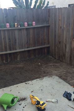 some tools are laying on the ground in front of a wooden fence and cactuses