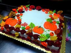 a decorated cake sitting on top of a metal counter covered in frosting and pumpkins