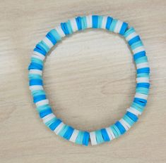 a blue and white beaded bracelet sitting on top of a wooden table