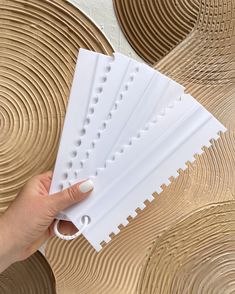 a person is holding four pieces of paper with holes in them on top of some circles