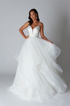 a woman in a white wedding dress posing for the camera with her hands on her hips