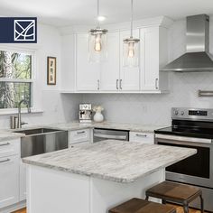 a white kitchen with marble counter tops and stainless steel appliances in the center, along with two stools