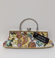 Elevate your style with this stunning Joymax Joy Collection Women's Floral Sequin Multicolor Ivory Handbag Purse. The trapezoid shape with a toggle closure and top handle strap in silver color adds a touch of sophistication. Perfect for parties, formal events, or any special occasion, this small-sized, lightweight clutch features a beautiful floral pattern that will make you feel like Belle from Beauty and the Beast. Crafted from high-quality silk material, this handbag has inner pockets to keep your essentials organized. The hardware color in silver complements the exterior color, making it a perfect accessory to add to your collection. The lining material in ivory color and the theme of flowers and happiness make it an ideal gift for your loved one. Fancy Purses, Trapezoid Shape, Silk Material, Ivory Color, Handbag Purse, The Beast, Beauty And The Beast, Silver Color, Top Handle