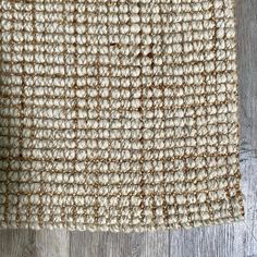 a close up view of the texture of a rug on a wooden floor with wood planks in the background