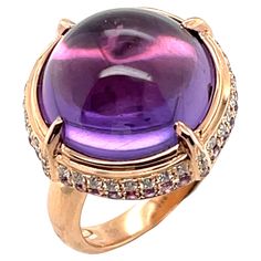 This striking ring features a 14.70 carat amethyst cabochon set in rose gold with bright pink sapphires and diamonds. The amethyst has beautiful crystalline purple color with pinkish highlights, accentuated by the 18k rose gold setting. A row of brilliant diamonds adorns the perimeter of the bezel, followed by a second row of sparkling pink sapphires that together create a stunning frame and make this ring eye-catching from all angles! Perfect for everyday and special occasions! Ring measures approximately 3/4" in diameter Round amethyst cabochon, 14.70 carats 32 round pink sapphires, .40 carats total 44 round brilliant-cut diamonds, .32 carats total Luxury Round Amethyst Ring With Rose Cut Diamonds, Rose Gold Frame, Pink Spinel, Pink Sapphire Ring, Sapphire And Diamond Ring, Gold Cocktail Ring, Gold Cocktail, Diamond Cocktail Rings, Cabochon Ring