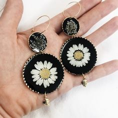 24k gold plated round dangle statement earrings made with real pressed flowers set in black resin. The small circle contains queen anne's lace, and the large circle contains a daisy. *Model is wearing this style in the clear resin. This listing is for the Daisy dangles with black resin. Perfect for nature lovers! These preserved botanical earrings are super lightweight and will make a statement! Pendants/charms: 24k gold plated brass Earring hoops: gold plated brass Thanks for shopping handmade! Elegant Pressed Flower Drop Earrings, Bohemian Dangle Jewelry With Pressed Flowers, Flower Shaped Brass Jewelry With Matching Earrings, Gold Drop Earrings With Pressed Flowers, Vintage Adjustable Jewelry With Pressed Flowers, Personalized Black Bohemian Jewelry, Round Flower Charm Earrings For Anniversary, Vintage Round Jewelry With Birth Flower Design, Bohemian Birth Flower Drop Earrings