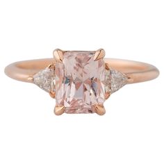 Embrace the allure of rarity with our exquisite 14K Rose Gold 3-Stone GIA Certified Padparadscha Sapphire Ring. The centerpiece, an ultra-rare unheated and completely natural radiant-cut Padparadscha sapphire, weighing 2.34 carats and measuring 7.47x5.99x5.49mm, boasts this stone's prized unmistakeable light pinkish-orange hue. Set with rounded claw prongs, it exudes a delicate charm that captivates the eye. Flanking this exceptional gem are two trillion-cut diamonds, totaling 0.25 carats, each Padparadscha Sapphire Ring, Pinkish Orange, Zierlicher Ring, Padparadscha Sapphire, Rose Orange, Claw Prong, Rose Gold Band, Sapphire Diamond Ring, Radiant Cut