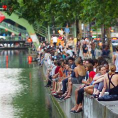 many people are sitting on the edge of a river