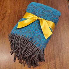 a blue and brown blanket with a yellow bow on it sitting on top of a wooden floor