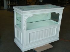 a white display case with glass doors on the top and bottom shelf is being worked on