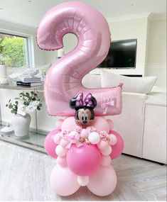 the balloon is shaped like a number two with minnie mouse on it and balloons floating in the air