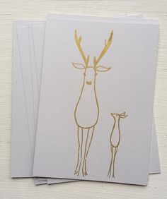 three cards with an image of a deer and a baby deer in gold ink on white paper